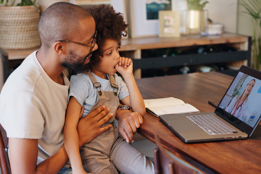 Father and son speaking to their dentist on the computer.