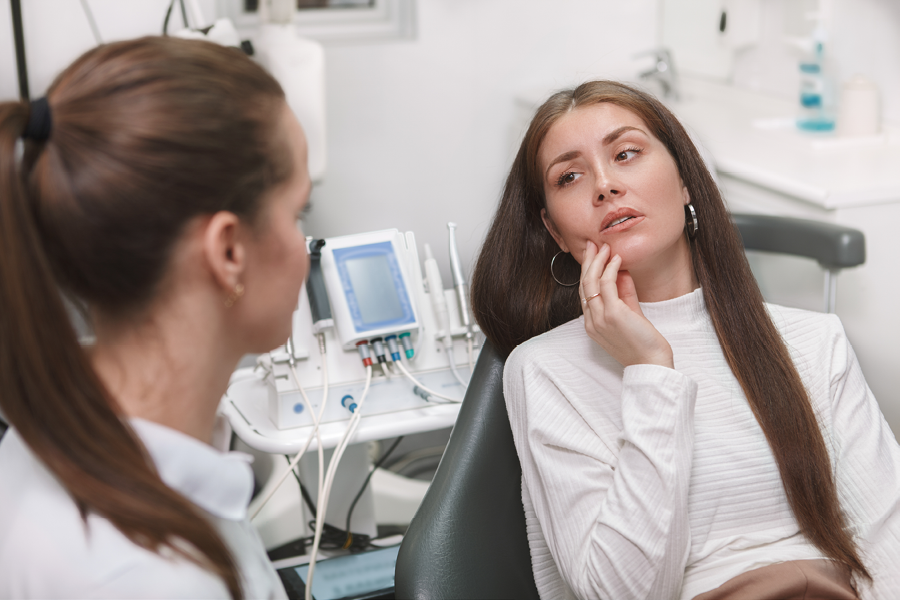 Person holding their jaw in pain at the dentist.