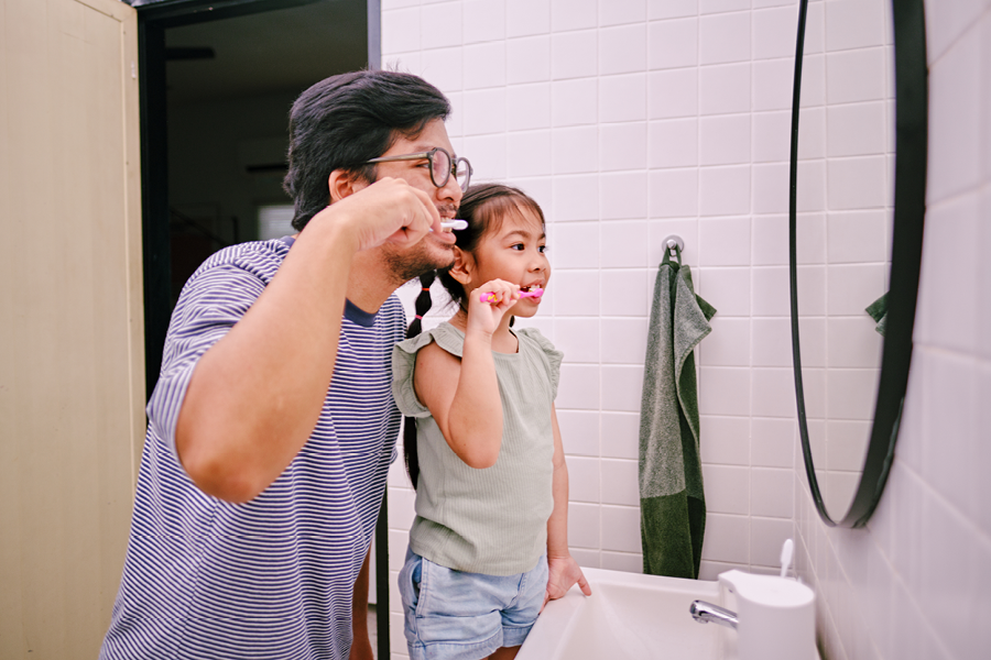 Father and daughter brushing their teeth.