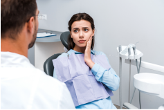 woman in dental chair with hand on cheek